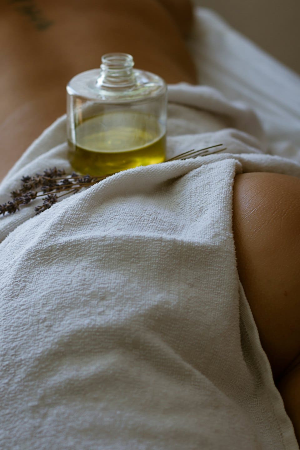 Massage oil and lavender rest on a spa towel.