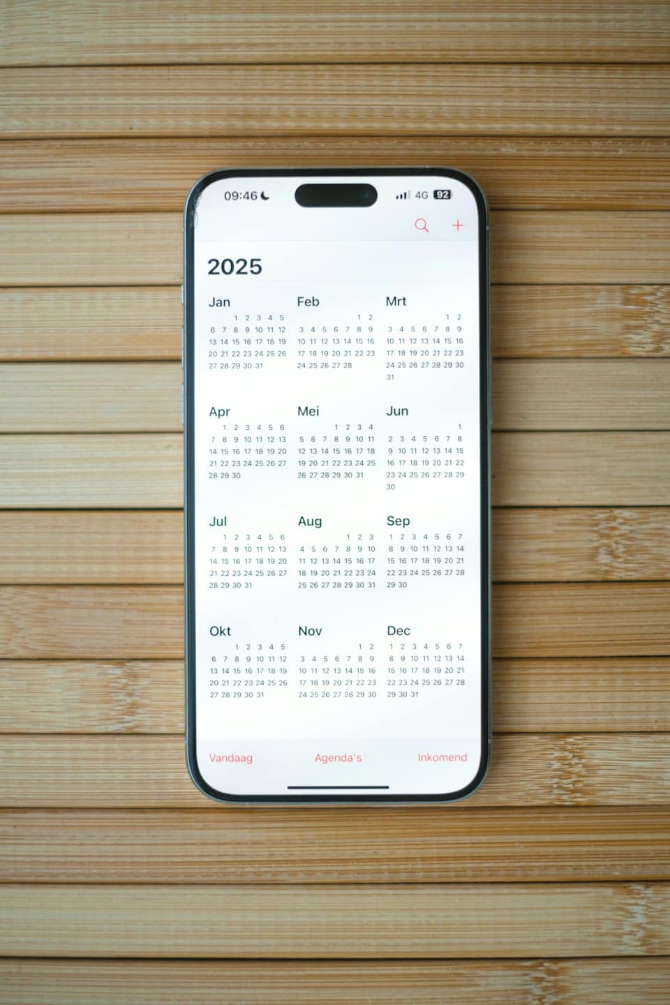 Smartphone showing 2025 calendar on a wooden table.